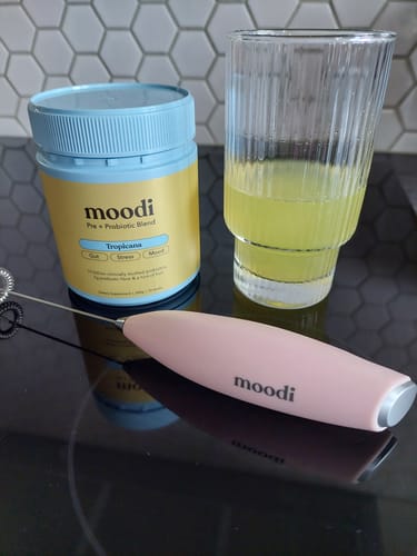 Customer's Tropicana Pre + Probiotic Blend tub on a counter next to a prepared drink and a mixer.