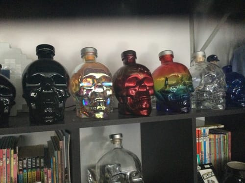 Reviewer's collection of various Crystal Head Vodka skull bottles displayed on a shelf.