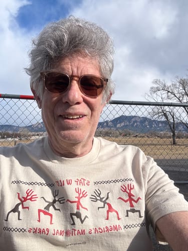 Reviewer smiling while wearing the beige Stay Wild Petroglyphs Tee outdoors.