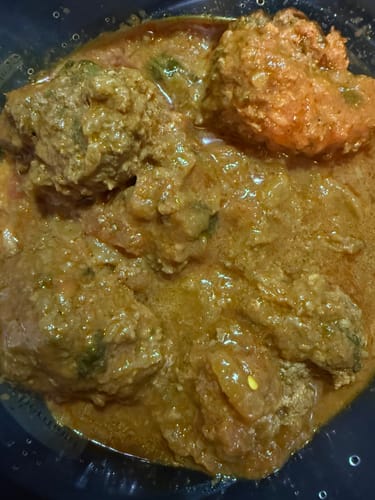 Close-up of a customer's cooked goat koftas made with Halal Goat Ground Meat in a savory curry.