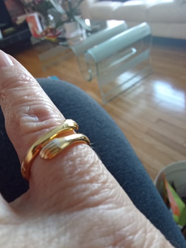 Close-up of a reviewer wearing the gold Hug From Heaven Ring on their thumb, showing the hugging hands design.