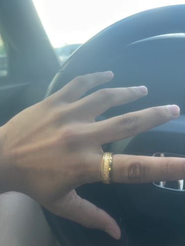 Customer wearing the textured gold Aureum ring while resting their hand on a steering wheel.