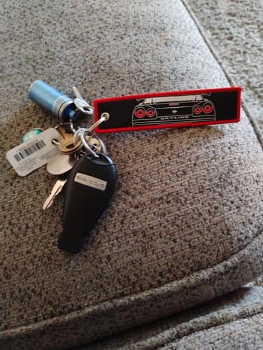 Customer's black and red SKYLINE JET TAG attached to a set of keys resting on a textured grey couch.