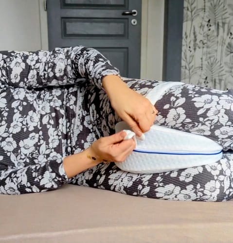 Cliente ajustant le Coussin Orthopédique Genoux Cellsius blanc entre ses genoux tout en étant allongée.