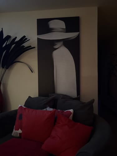 Customer's black and white canvas print of a woman in a large hat, displayed on a wall above a sofa.