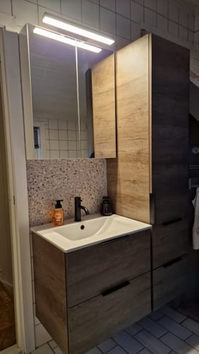 Kundens London terrazzo selvklebende fliser brukt som en stilig bakvegg over vasken på et bad.