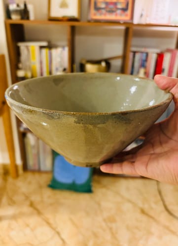 評論者用單手拿著一個大型的Lagman碗，以展示其尺寸和輕巧的特性。