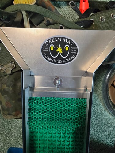 A customer's close-up of the green Dream Mat installed in a metal sluice box, secured by the clamp.