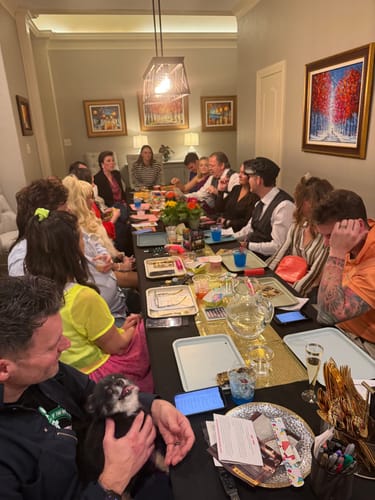 Reviewers gathered around a long dinner table playing the 1980s Murder Mystery Game.