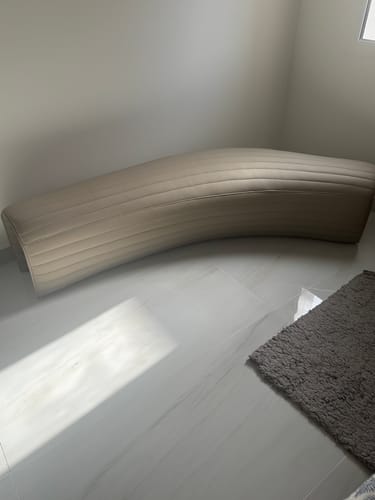 Customer's beige Dunecrest Bench placed in a corner on a light tiled floor.