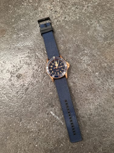 Customer's watch featuring the blue Canvas & Rubber strap with a black buckle, lying on a textured grey surface.
