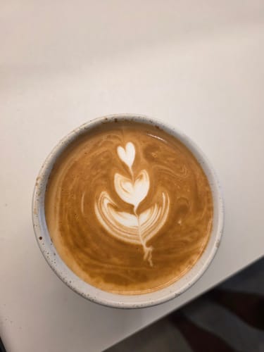 Customer's Brazil Santos coffee served as a latte with delicate heart-shaped latte art.
