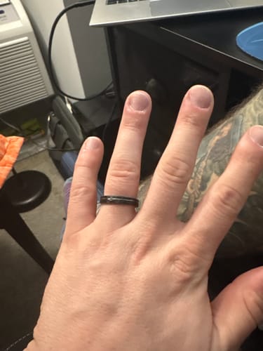 Customer's hand wearing a new dark-colored ring they received after an exchange.