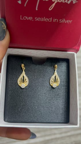 Customer holding an open red jewelry box showing the Golden Glint Earrings on a black insert.