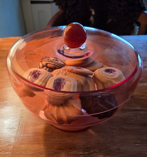 Klant toont de roze Duo stolp gevuld met verschillende koekjes op een tafel.