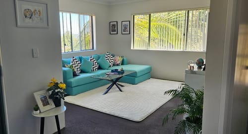 Customer's Buttermilk Beige Relax Mat in a stylish living room in front of a bright teal sofa.