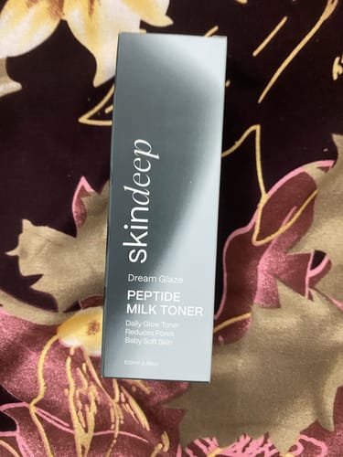 Customer's box containing the Dream Glaze Peptide Milk Toner resting on a patterned surface.