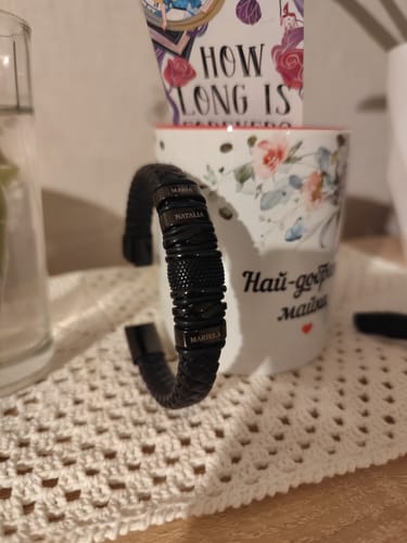 Customer's black bracelet with several personalized name beads, shown close-up on a table.