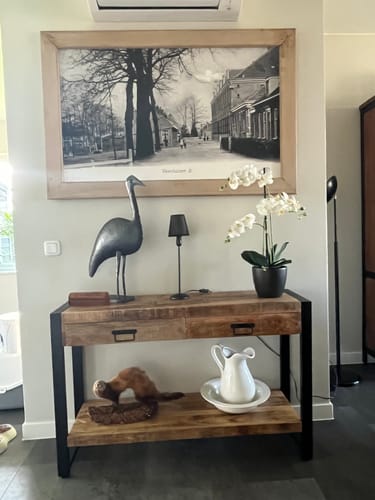 Klantfoto van de mangohouten sidetable in een hal, gedecoreerd met een lamp, een orchidee en een beeldje.