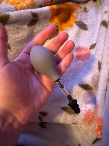 Customer holding the ZŌK Device in their palm, showing the grey rubber bulb and applicator tip.