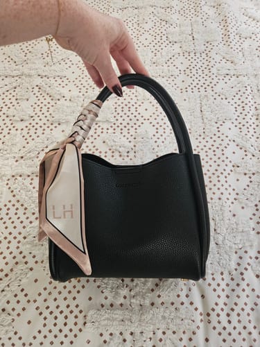 Customer holds the black Steffie Mini Tote Bag, showing the decorative scarf tied to its top handle.