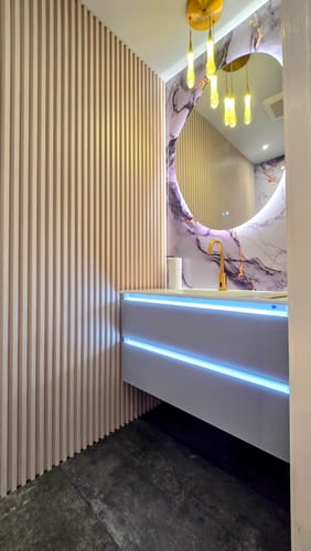 Customer's side view of the Catalyst LED Floating Vanity with blue lights on, installed in a modern bathroom.