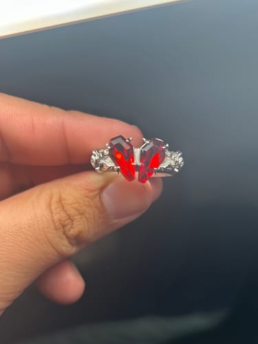 Customer holding the Promise Ring, showing its two coffin-shaped, crimson red stones against a dark background.