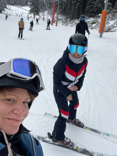Reviewer on a snowy slope wearing the slim-fit one-piece ski suit with red and white color-blocking.