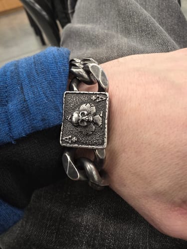 Close-up of the Revenant's Wrath Ace of Spades Cuban Link Bracelet on a reviewer's wrist, focusing on the skull centerpiece.