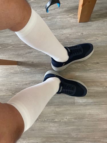 Customer wearing the white, knee-high Performance Eucalyptus Compression Socks with dark sneakers.