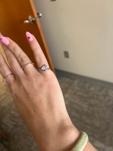 Customer's hand wearing the sparkly Pia Ring with its wave band on the pinky finger.