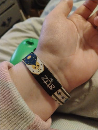 Customer wearing the reversible Allow No Harm Bracelet, showing the hamsa hand design and black tag on their wrist.