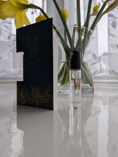 Customer's small Honeyberry fragrance sample bottle and card on a white table with daffodils.