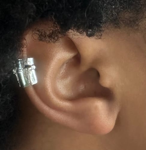 Close-up of a customer wearing a detailed silver ear cuff on the upper part of their ear.