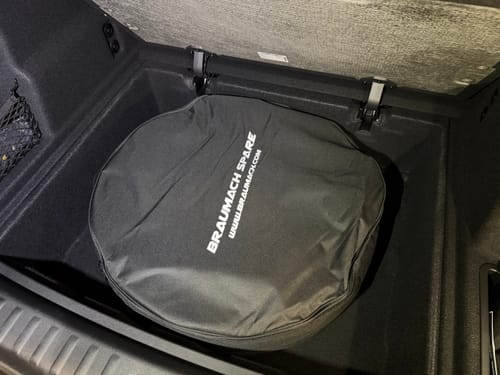Reviewer's Braumach space saver spare wheel kit in its black bag, fitting inside the trunk storage compartment of a BMW X1.