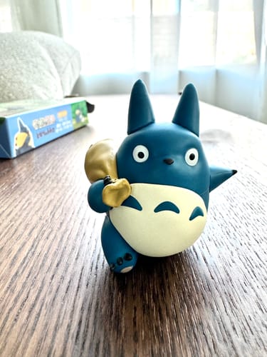 Customer's assembled blue Chuu-Totoro 3D Jigsaw Puzzle figure sitting on a wooden table, holding a yellow sack.