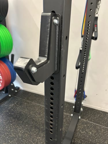 Customer's black Riot Sandwich J-Hook attached to a modular power rack upright in a gym setting.