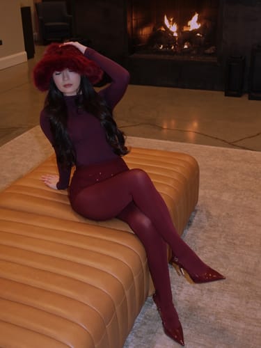 Reviewer sitting in front of a fireplace wearing the Crystal High Waisted Hot Pants styled with thick burgundy tights.