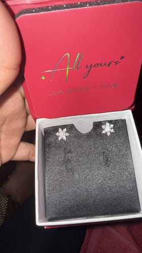 Reviewer holding open a red jewelry box to show the Silver Flowery Snowflake Studs.