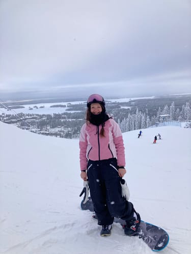 Reviewer on a snowy mountain with a snowboard, wearing the baggy waterproof snow pants.