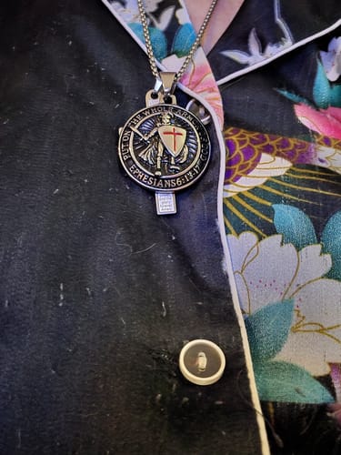 Reviewer wearing the St. Michael the Archangel Keychain as a detailed pendant on a chain necklace against their shirt.