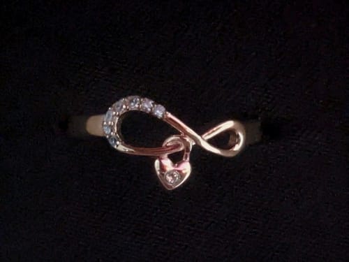 Customer's close-up of the Rose Gold Infiniheart Ring showing the dangling heart charm on a black background.