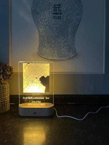Kundenfoto: Das personalisierte Nachtlicht 'Notre Moment' leuchtet auf einem Tisch, angeschlossen mit seinem weißen Kabel.