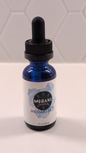Customer's blue glass bottle of Meraki Blu Methylene Blue with a dropper on a white counter.