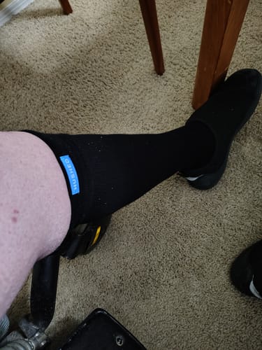 Customer wearing a black Performance Eucalyptus Compression Sock, showing the knee-high fit and blue brand tag.