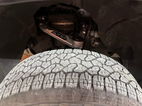 Customer's silver aluminum upper control arm installed in their truck's wheel well.