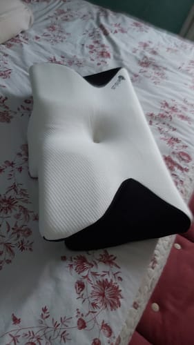Avis d'un client sur son coussin d'alignement cervical Cellsius, vu sur un lit à motifs.