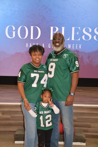 Reviewers and a child wearing their custom green and white authentic football jerseys.