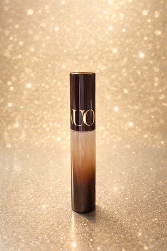 Reviewer's high-coverage concealer in an ombre tube against a glittery background.