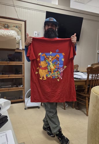 Reviewer holding up a red Disney T-shirt with a colorful Winnie the Pooh and friends graphic.